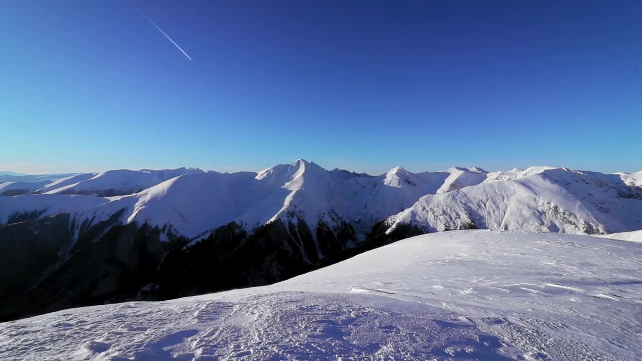 在阳光明媚的日子里，tracki的积雪覆盖的小山和山脉的壮丽景色视频素材