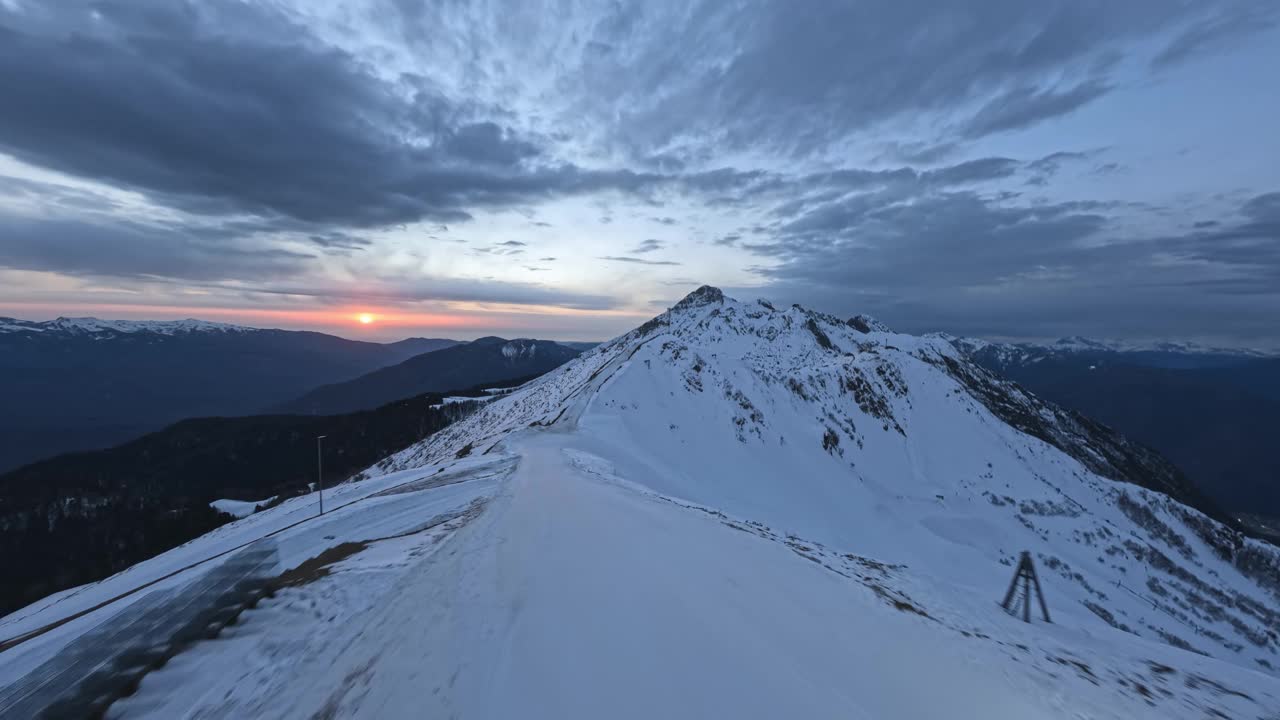 FPV无人机向前拍摄冬季傍晚山谷雪崖高峰海拔太阳视频素材