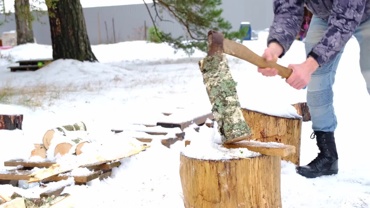 一个人在冬天的雪地里用斧头劈柴。替代供暖，木材采伐，能源危机视频素材