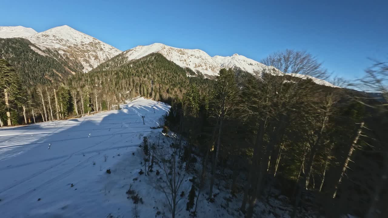 冬季滑雪场山坡环绕山谷森林树木由雪山的山峰视频素材