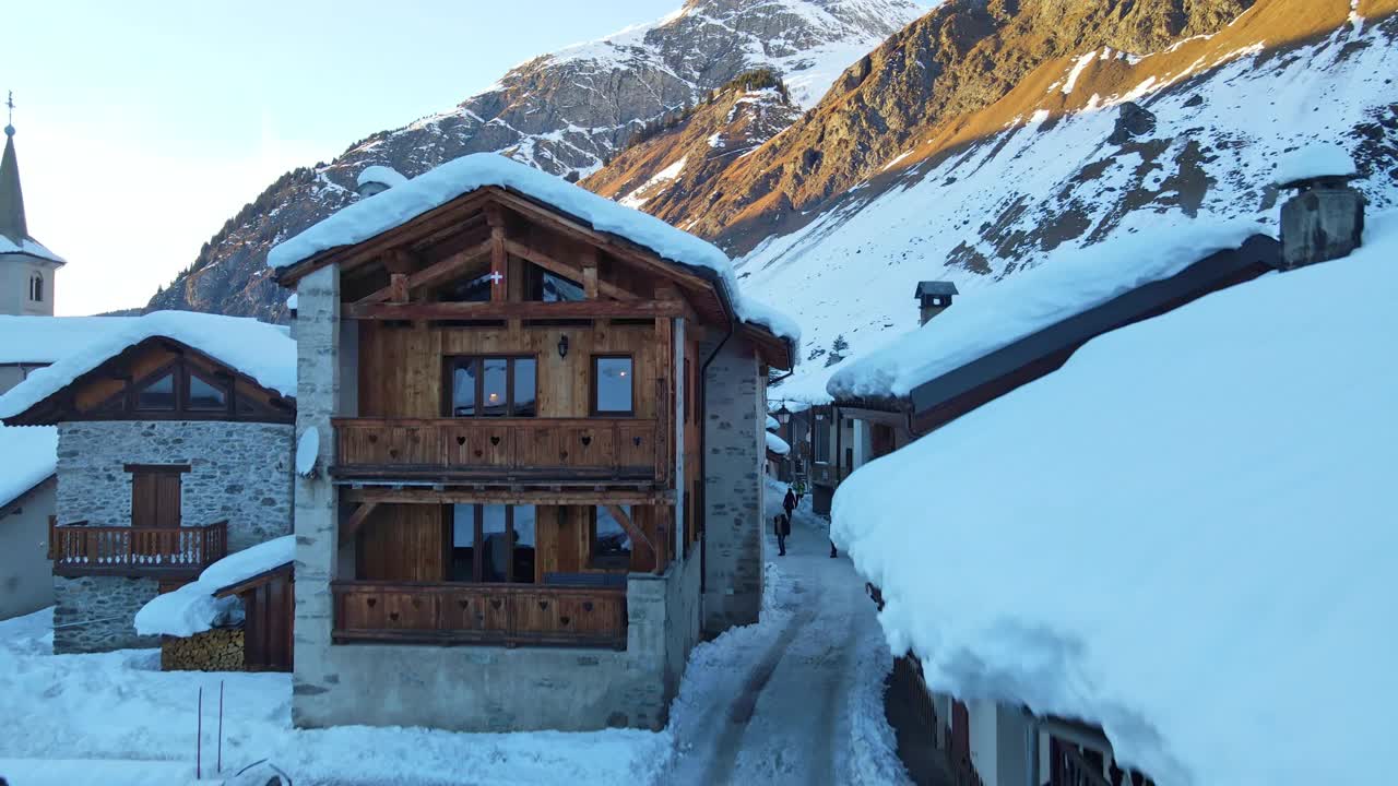 瑞士阿尔卑斯山在阳光下被雪覆盖的惊人全景，岩石山脚下的小游客村，著名的滑雪胜地和游客休闲中心。瑞士冬季自然之美视频素材