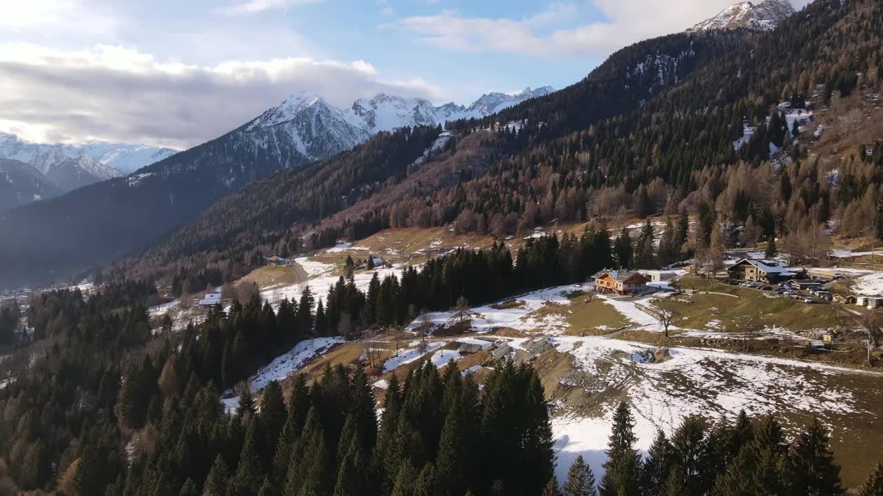 瑞士冬季的自然美景，阳光下雪天瑞士阿尔卑斯山的鸟瞰图，松树林中的游客村庄，瑞士山心的木屋、小木屋和房屋。石山山峰被雪覆盖而成视频素材