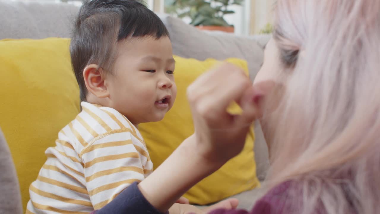 过肩慢镜头，年轻美丽的亚洲女性母亲在家里快乐地和她可爱的小儿子玩耍。视频素材