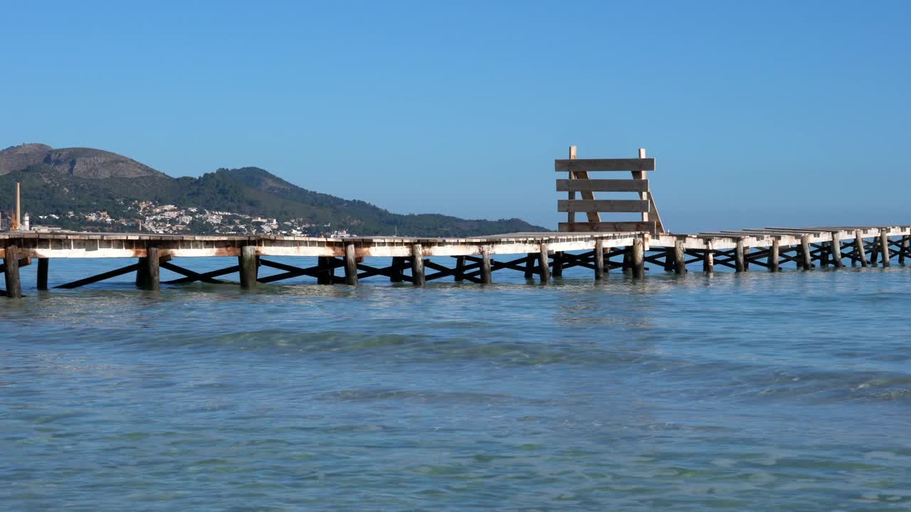 在一个阳光明媚的日子里，地中海海浪轻柔地到达木桥的特写视频下载