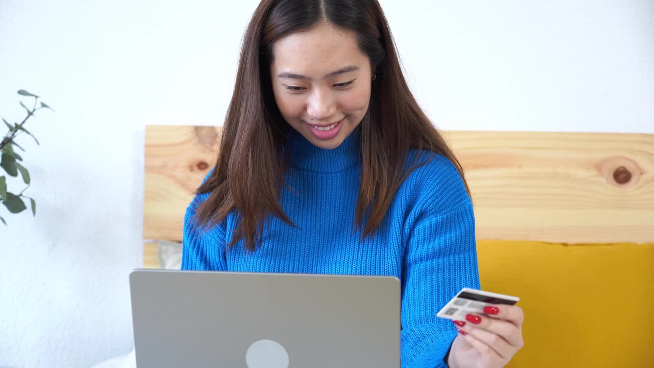 微笑的女人在床上用笔记本电脑网购视频素材