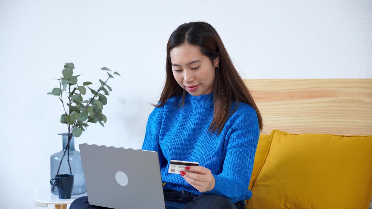 微笑的女人在床上用笔记本电脑网购视频素材