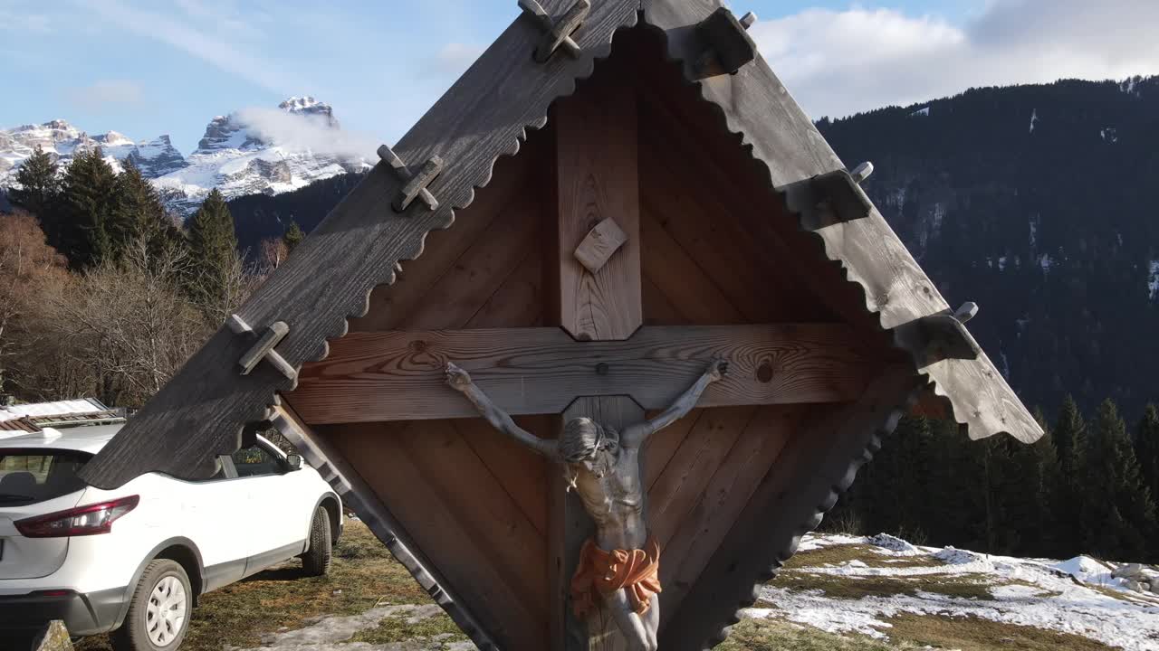 木制十字架与耶稣基督雕像十字架作为历史纪念碑，在山村与旅游目的地，惊人的全景岩石山脉覆盖着雪，云雾触摸小山山峰。瑞士的自然之美视频素材