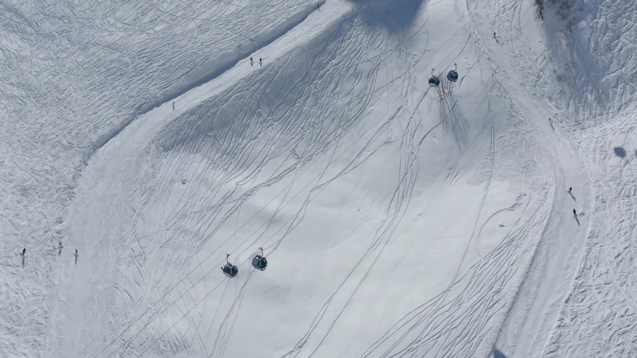 鸟瞰图，人们在山谷度假胜地的轨道上乘坐滑雪板和索道风景视频素材