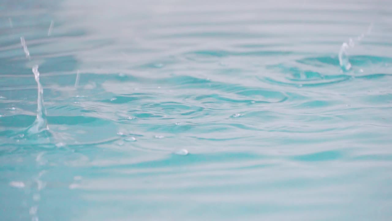 慢镜头拉近了水池里的雨滴。放松时间和自然的背景。视频素材