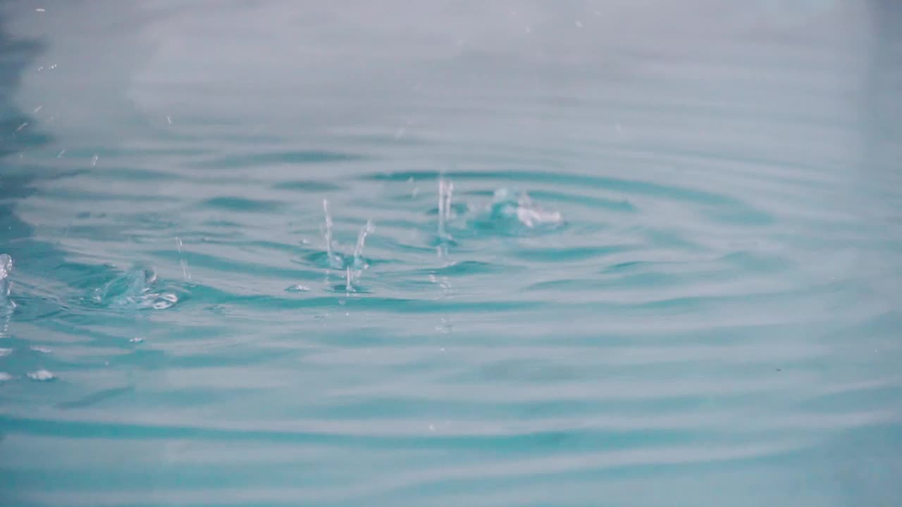 慢镜头拉近了水池里的雨滴。放松时间和自然的背景。视频素材