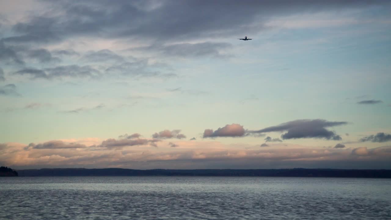 一架飞机在日出时飞过普吉特海湾的锁定镜头视频素材