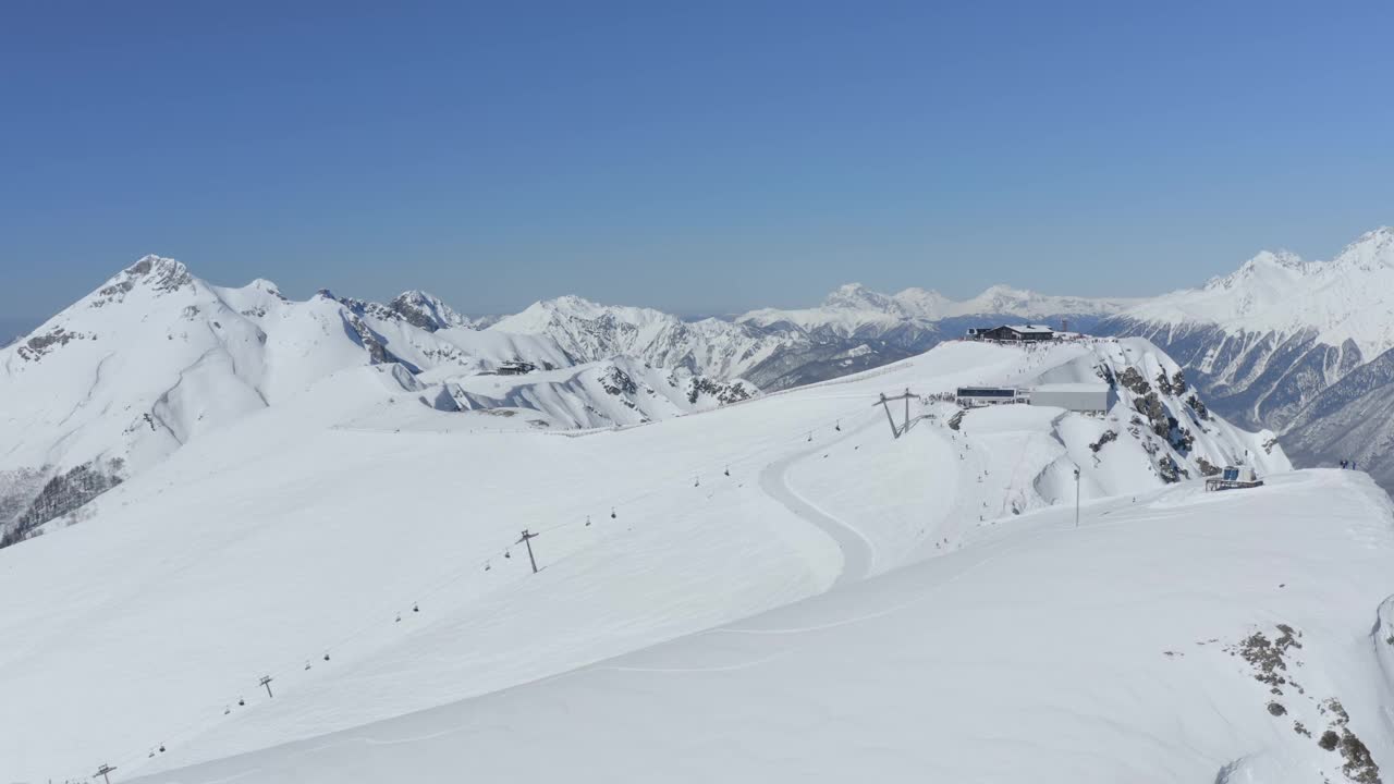 阳光明媚的滑雪场景观雪山活跃的极限运动骑手滑雪单板滑雪鸟瞰视频素材