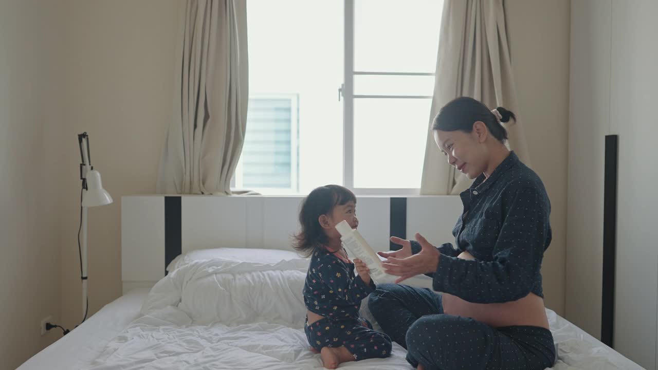 亚洲女婴很高兴，很兴奋摸着妈妈的肚子，里面的第二个婴儿在动，她是她妈妈的第二次怀孕。视频素材