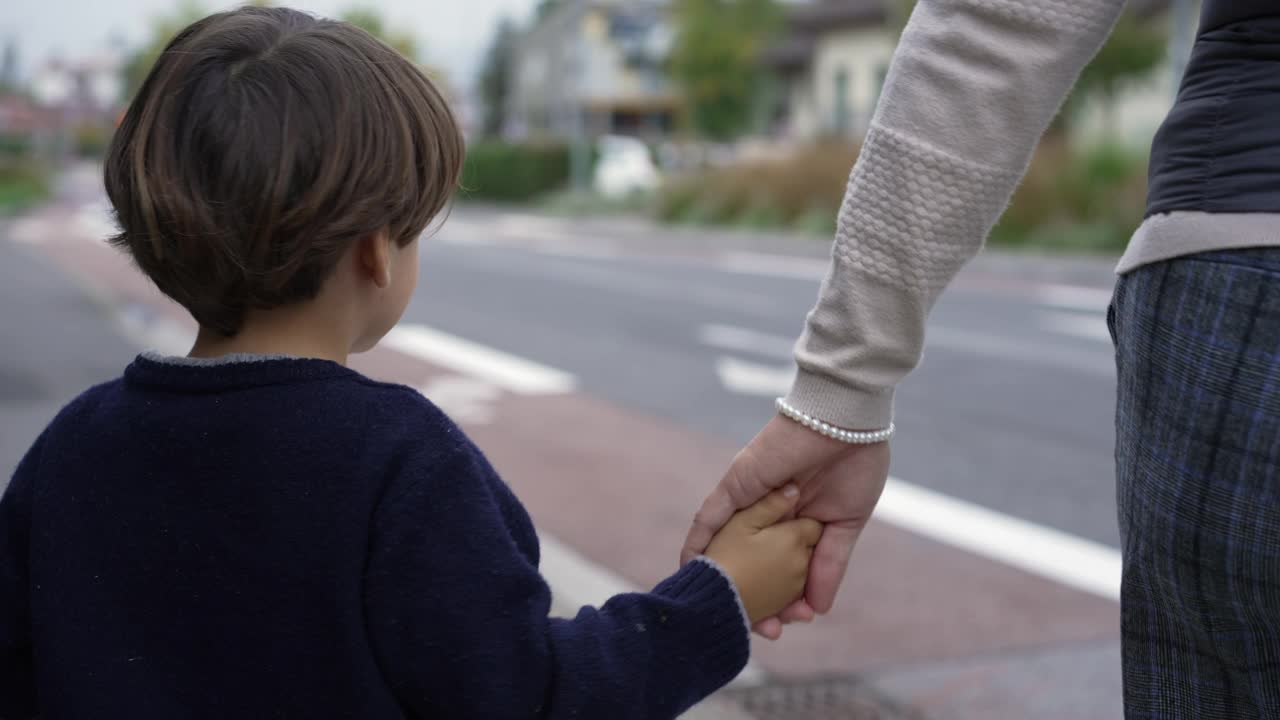 孩子牵着母亲的手等着在人行横道过马路。家族信托概念。父母和孩子手牵着手视频素材