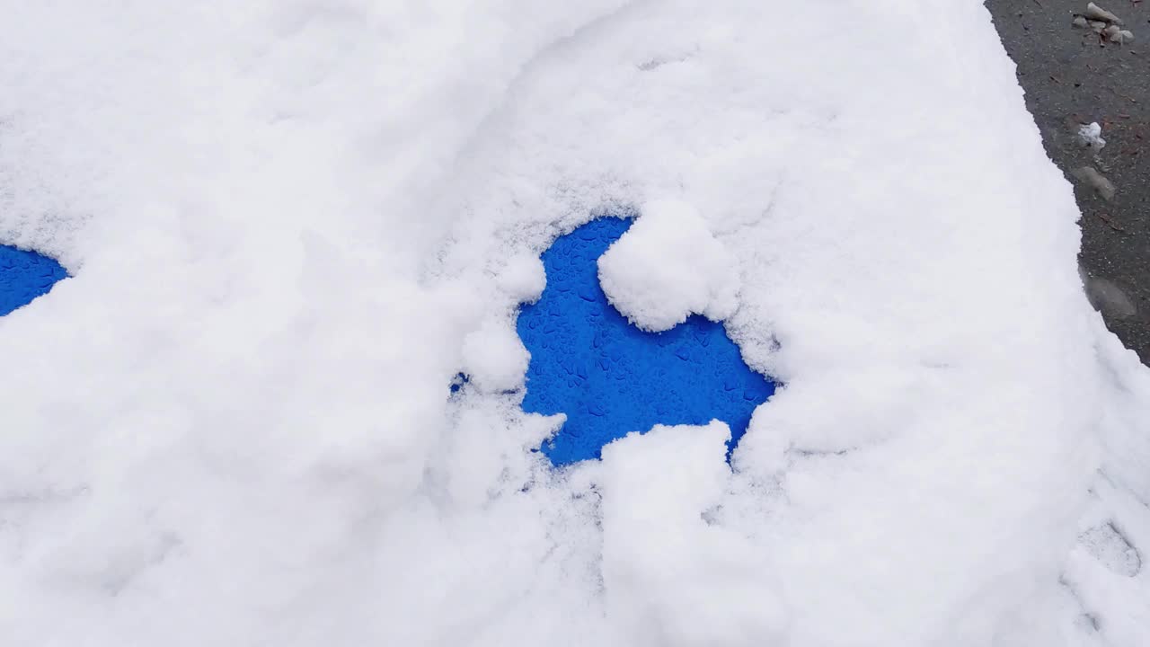 刚落下的雪在蓝色汽车的引擎盖表面视频素材