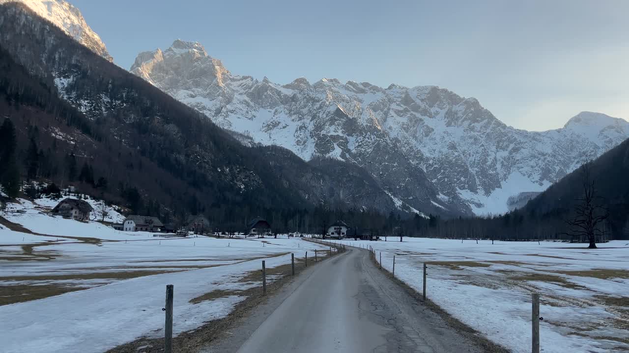 风景如画的山景。第一人称的观点沿着道路沿着一个被雪覆盖的路边走向一个高高的雪山在黄昏视频下载