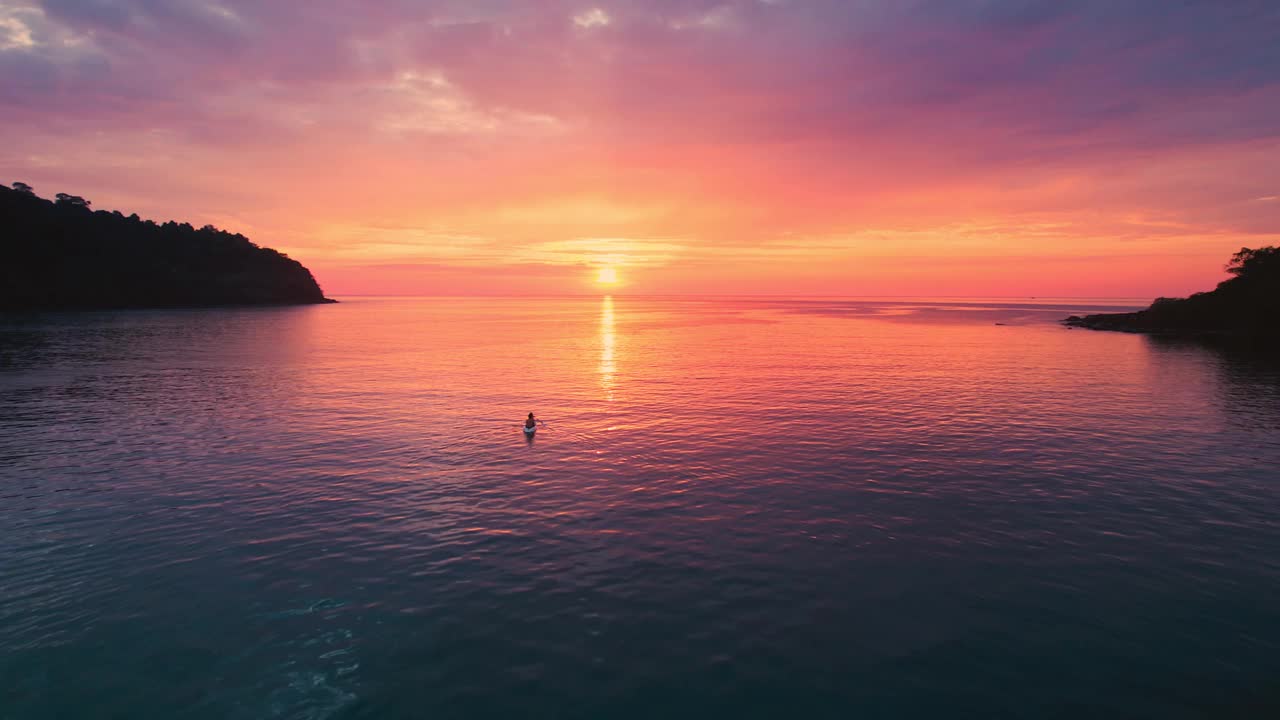 俯瞰热带海面上美丽的日落，游客划着独木舟，在夏天欣赏美景视频素材