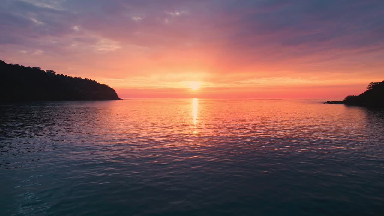 在热带海面上空飞行的鸟瞰图，在夏天，美丽的日落闪闪发光视频素材