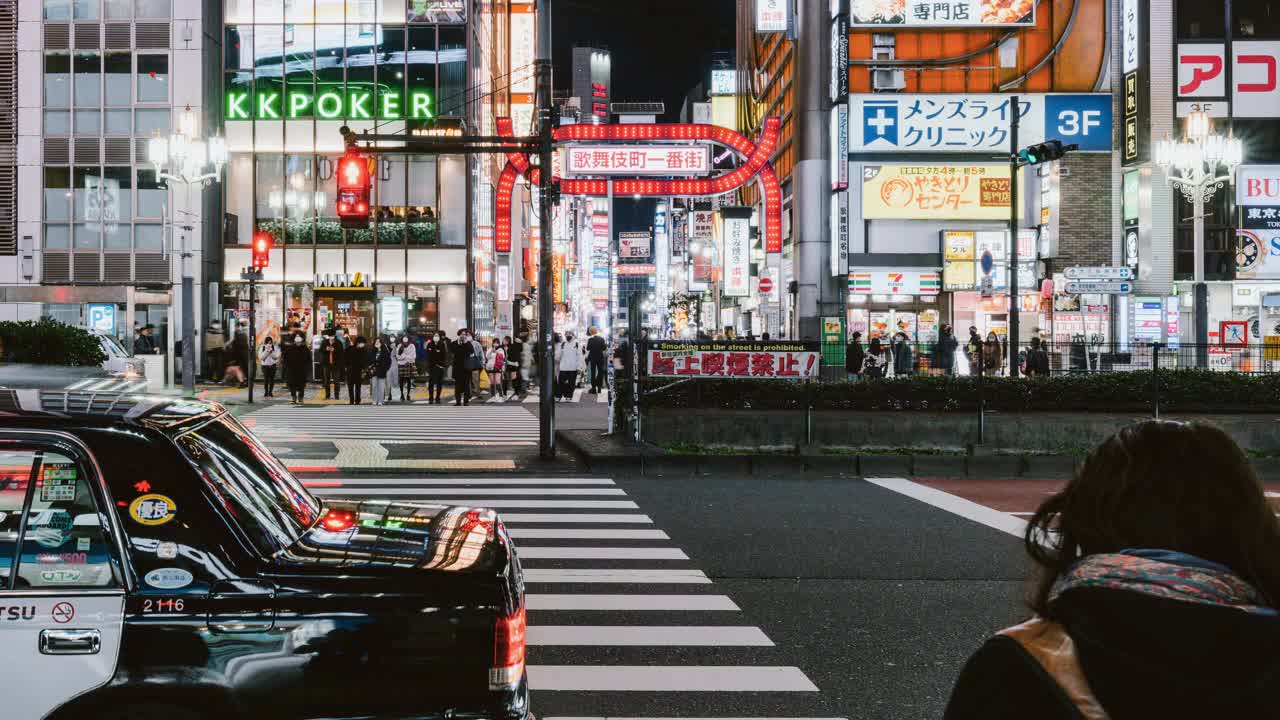 东京新宿歌舞伎町街区的日本人、亚洲旅行者穿越马路、汽车交通运输的夜间城市景观。亚洲旅游还是日本的交通概念视频素材