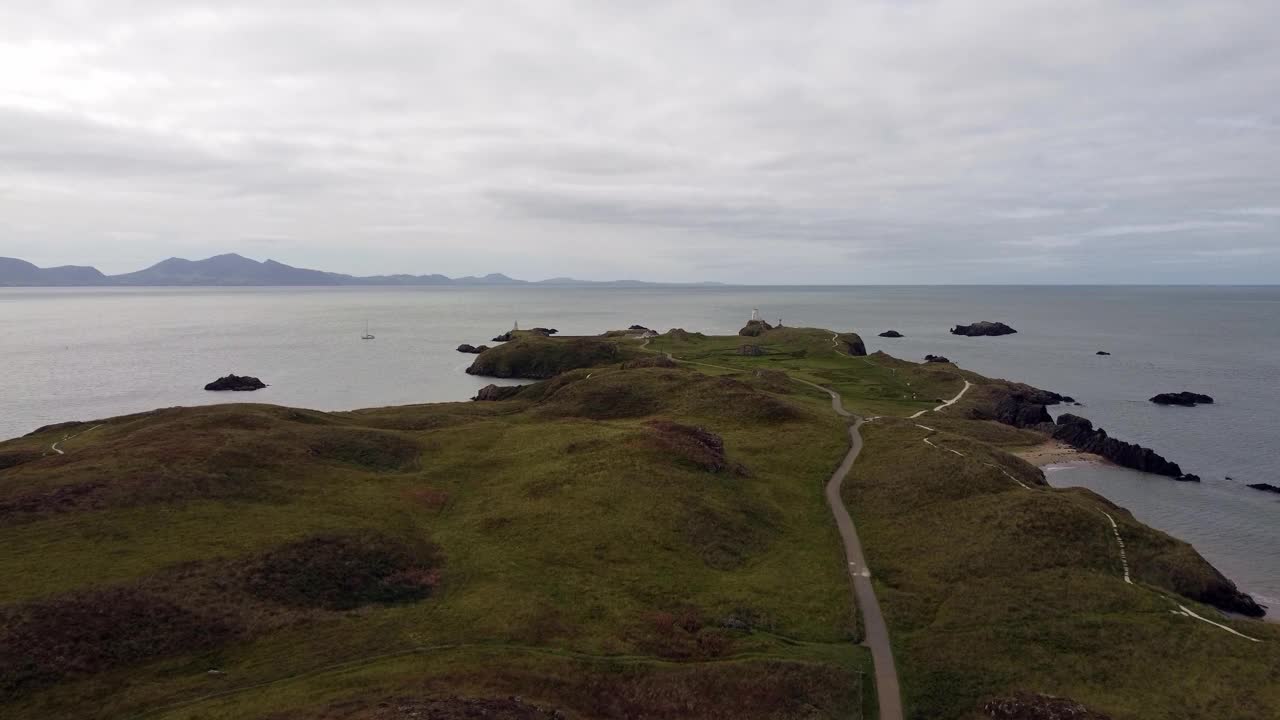 空中上升视图Ynys Llanddwyn岛安格尔西岛沿海步行道与斯诺登尼亚山脉横跨爱尔兰海视频素材