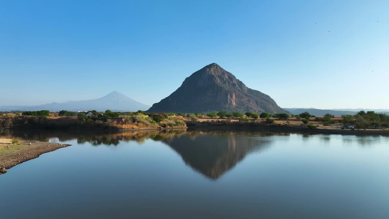 美丽的水反射的El Chumil山与Popcatepetl火山的背景，上升的空中与复制空间在天空视频素材