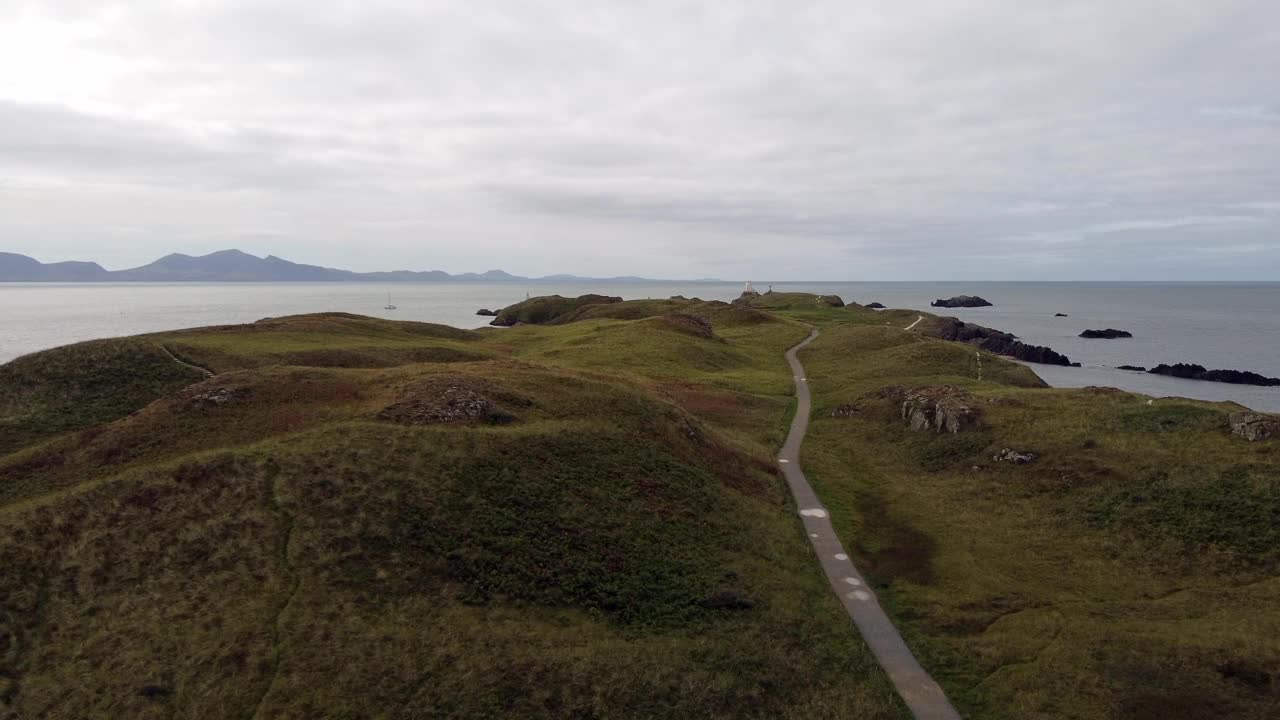 空中推视图Ynys Llanddwyn岛安格尔西岛沿海步行道与斯诺登尼亚山脉横跨爱尔兰海视频素材