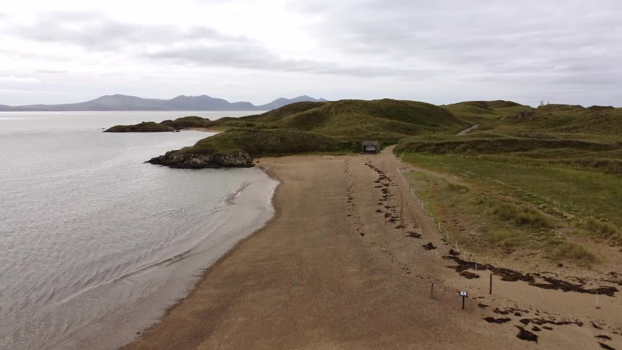 鸟瞰Ynys Llanddwyn岛安格尔西岛海岸沙质步行道与斯诺登尼亚山脉横跨爱尔兰海视频素材