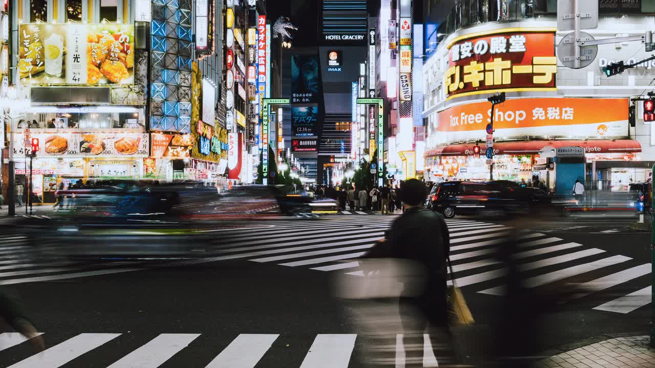 东京新宿歌舞伎町哥斯拉街的日本人、亚洲旅行者穿越马路、汽车交通运输的夜间城市景观。亚洲旅游旅游或日本交通视频素材