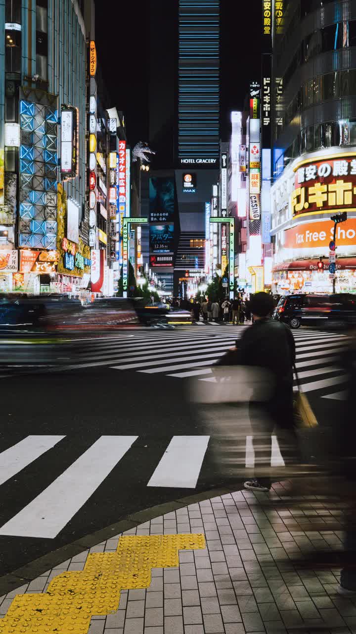 东京新宿歌舞伎町哥斯拉街的日本人、亚洲旅行者穿越马路、汽车交通运输的夜间城市景观。亚洲旅游旅游或日本交通视频素材