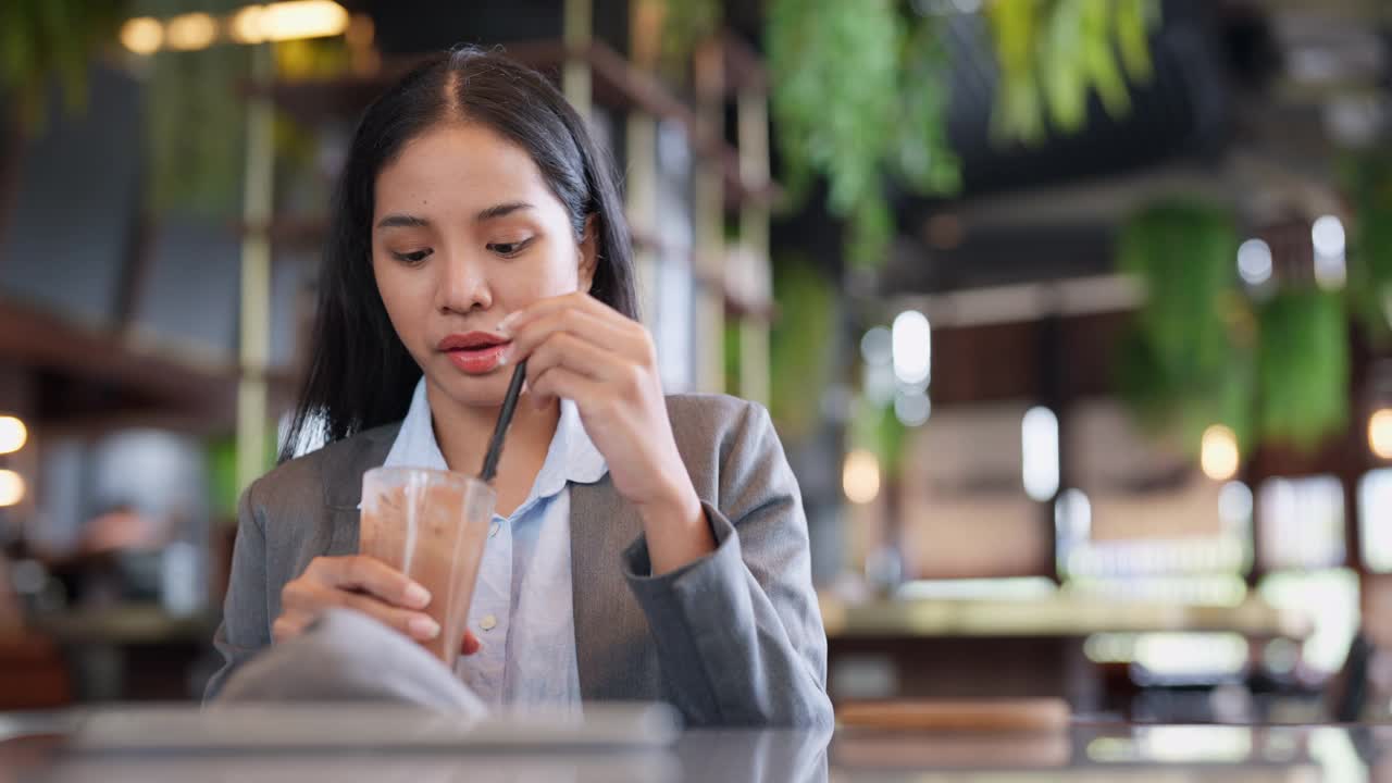 西装革履的女商人坐在现代化的咖啡店里，喝着冰巧克力，和同事聊天。自由职业者在有咖啡的合作空间工作。商业和新的工作生活方式。咖啡休息和放松时间视频素材