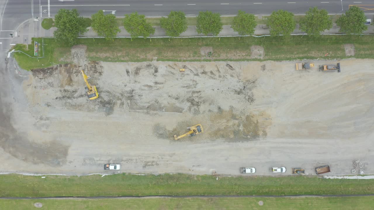 平滑的空中俯瞰着空旷的建筑工地上一起工作的挖掘机。视频素材