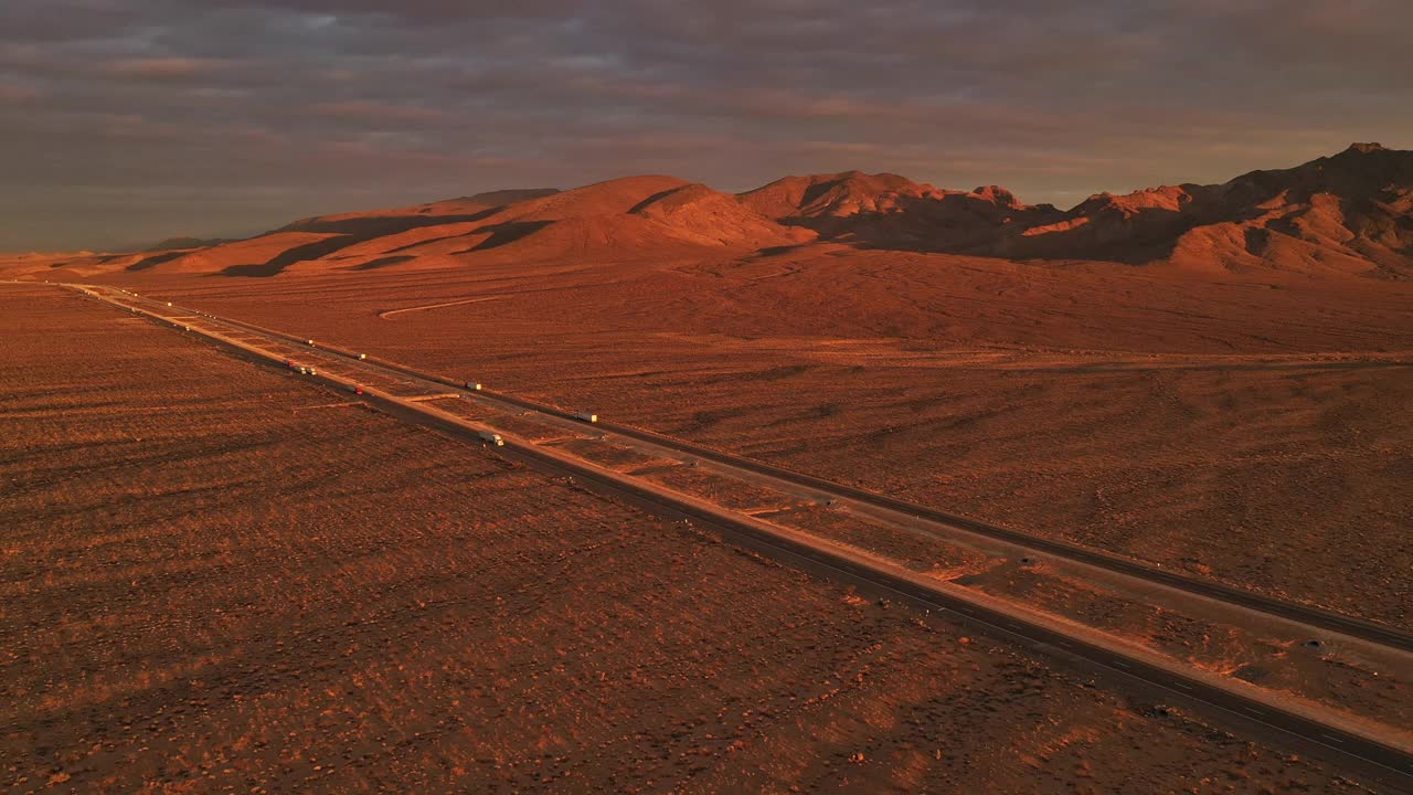 繁忙的高速公路上，汽车和卡车在日落时分沿着笔直的沙漠公路行驶视频素材