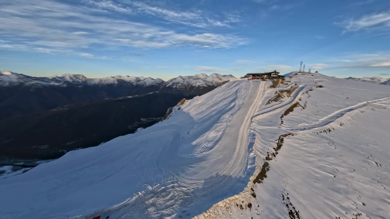 FPV无人机向前拍摄冬季滑雪场晚山山谷雪崖峰视频素材