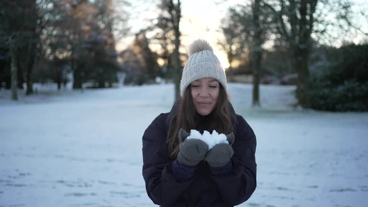 女子站在丘陵雪景吹雪从她的手套视频素材