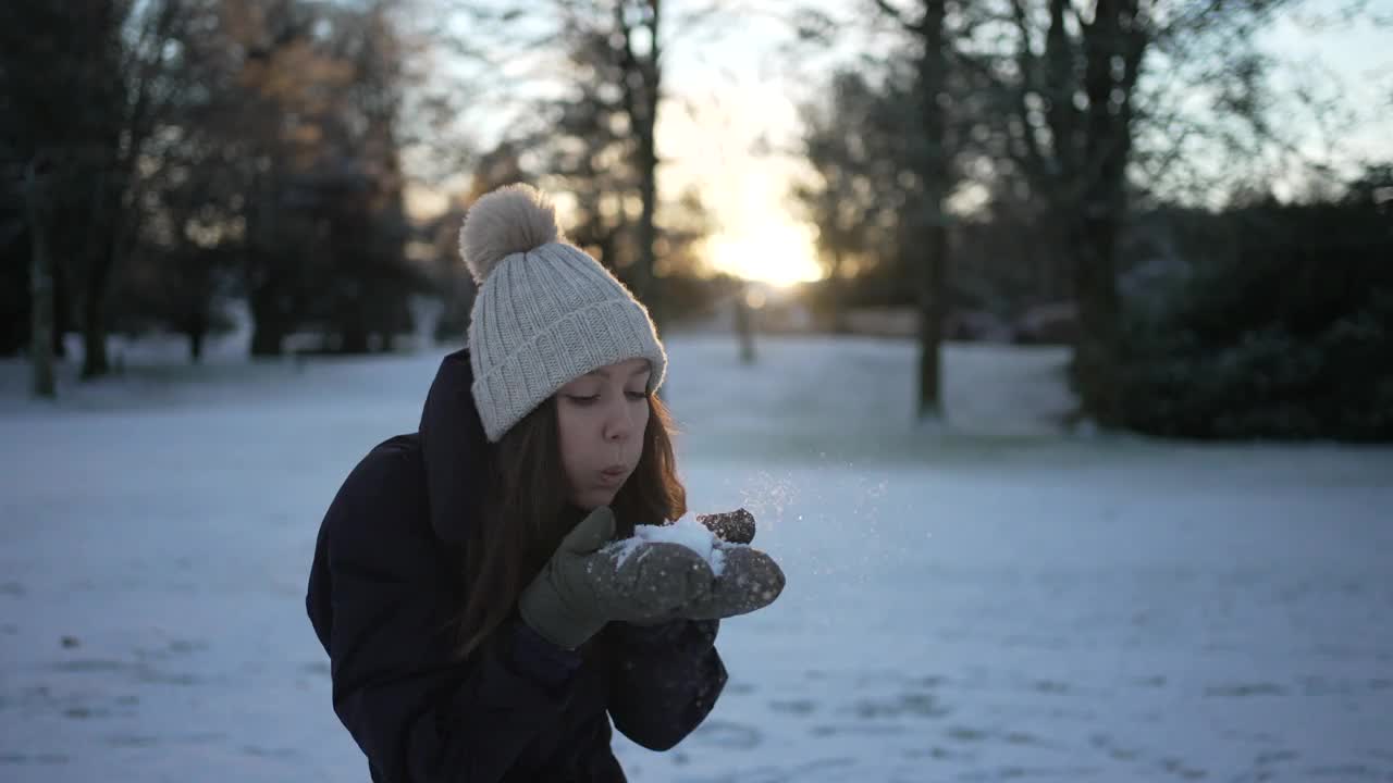 女子站在丘陵雪景吹雪从她的手套视频素材