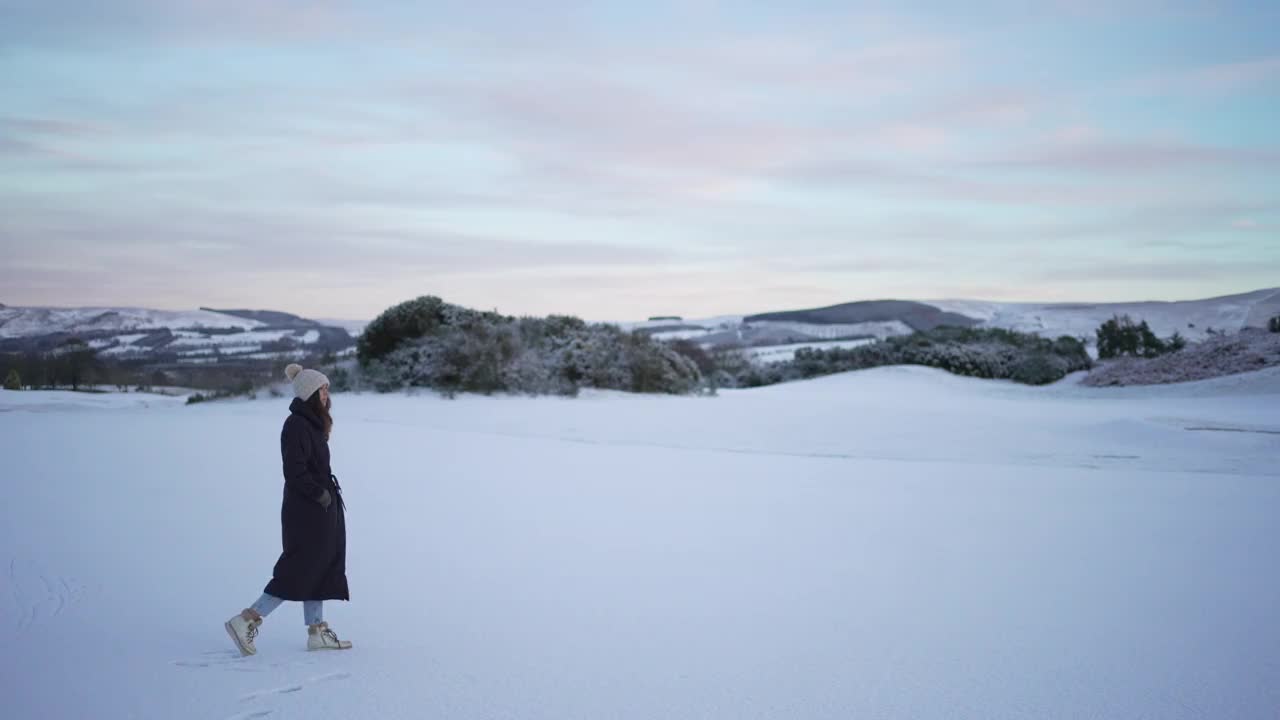 穿着冬衣的女子走在雪景上视频素材