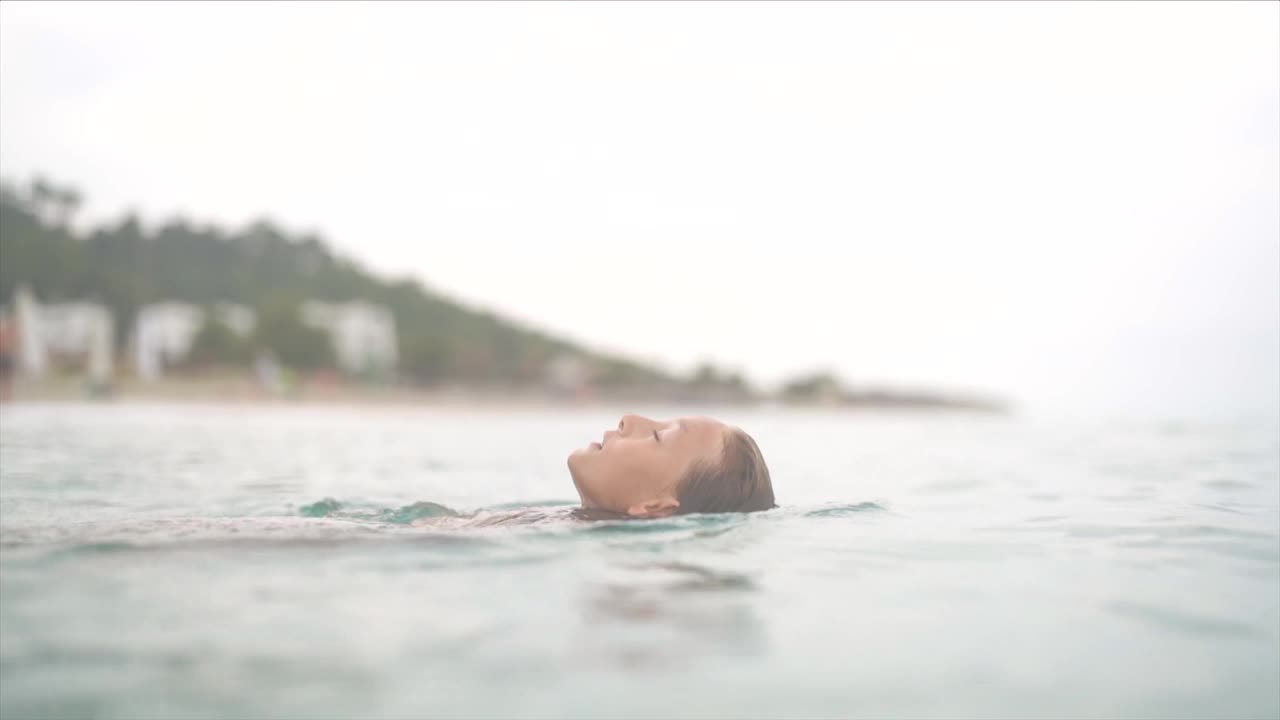 一个年轻的女孩在一个炎热的夏天下午在海里放松视频素材