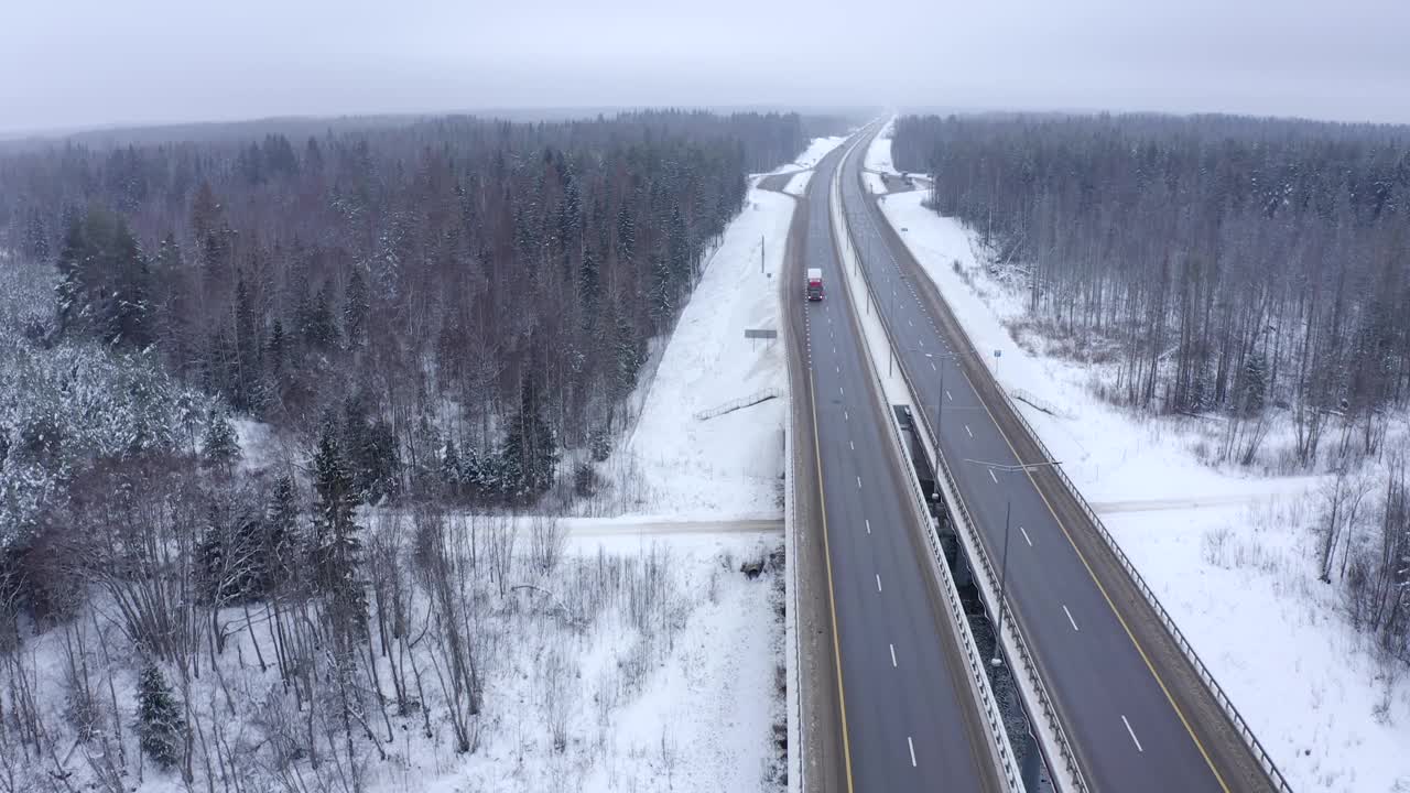 一辆卡车行驶在一座桥上，桥上的道路被积雪覆盖视频素材