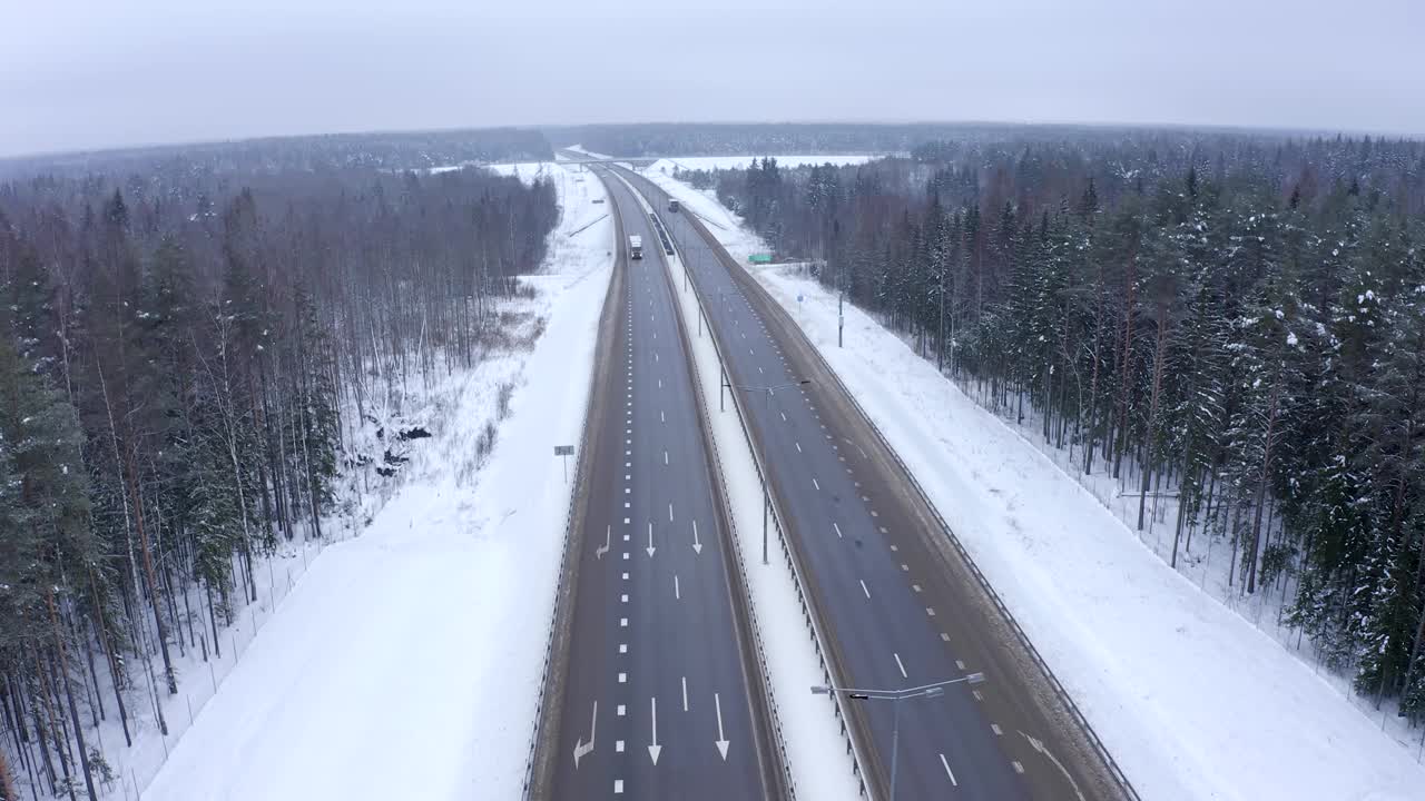 一辆车顶上有白色遮阳篷的卡车行驶在白雪覆盖的森林里的高速公路上。视频素材