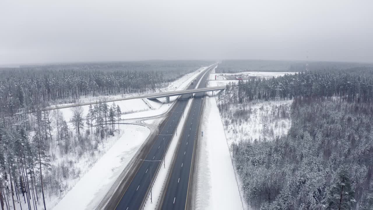 无人机在冬天的道路上与一辆过往的汽车一起飞行。前视图视频素材