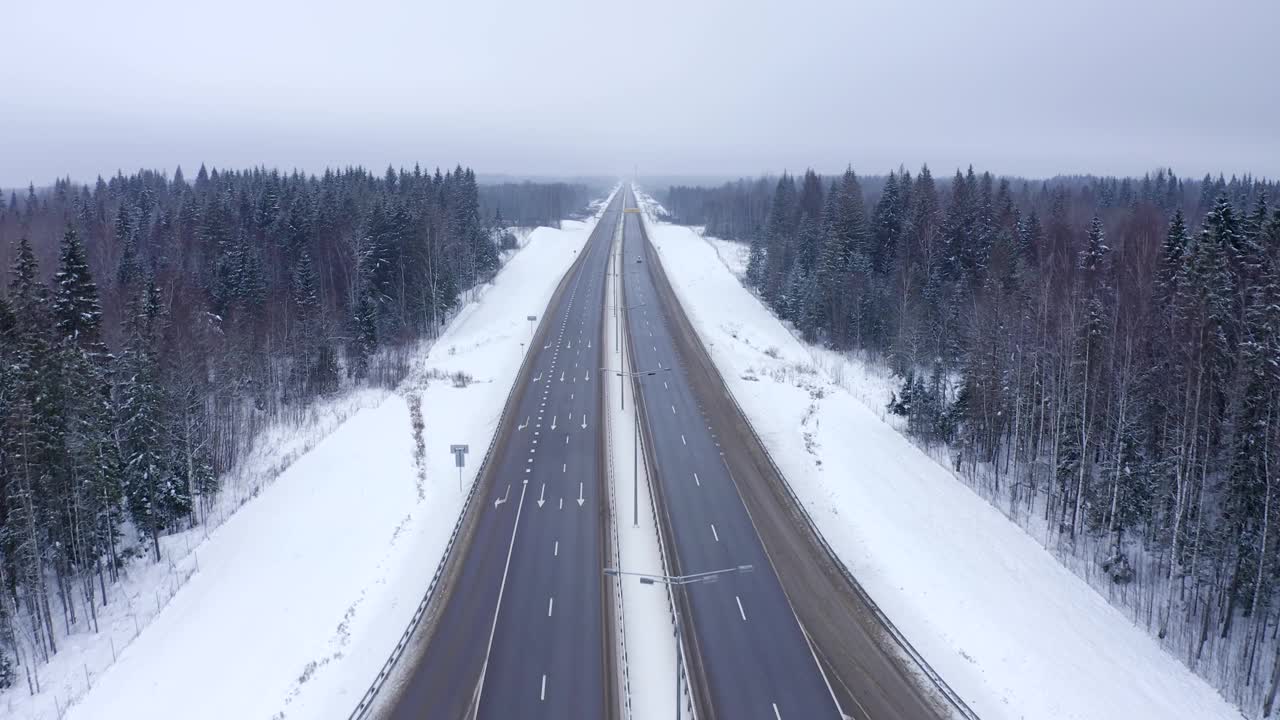 冬天，在白雪覆盖的森林公路上，一辆黄色的货车驶过。视频素材