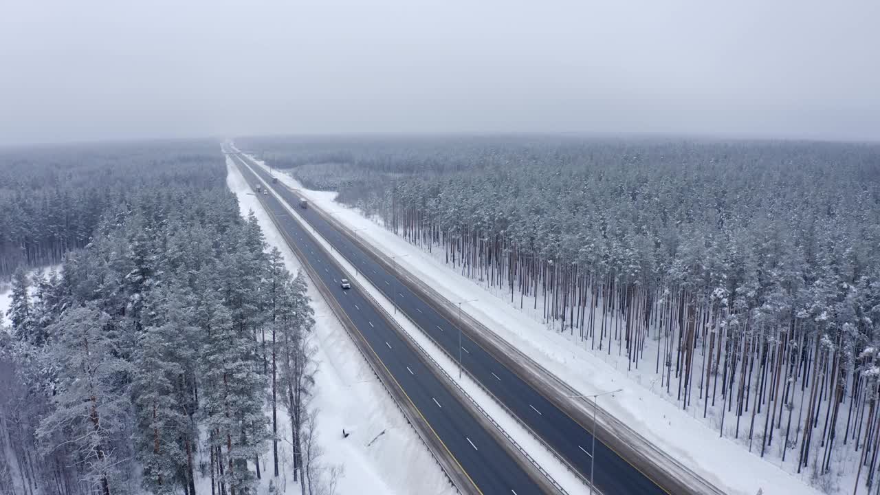 白色的汽车和白色的货车行驶在马路上的树林在雪的前面视频素材