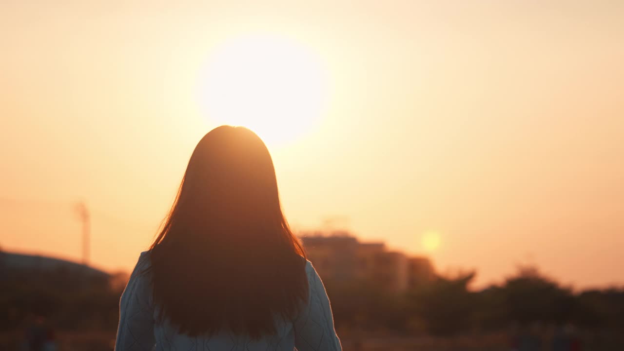 快乐的女人在日落时用手做心形，女人用太阳耀斑展示爱的符号手势，夏天的梦想视频素材