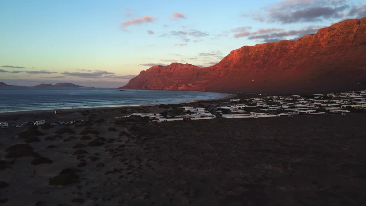 日落在海滩上，翻越悬崖，与海为伴。太阳沐浴着悬崖。自然景观是火山。法马拉加那利群岛视频下载