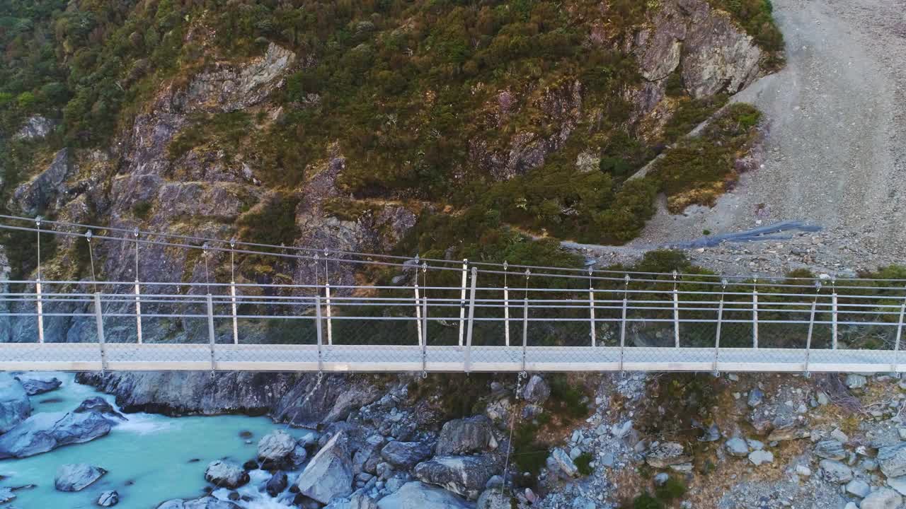 徒步旅行者沿着悬索桥在奔流的河流激流到雪山视频素材