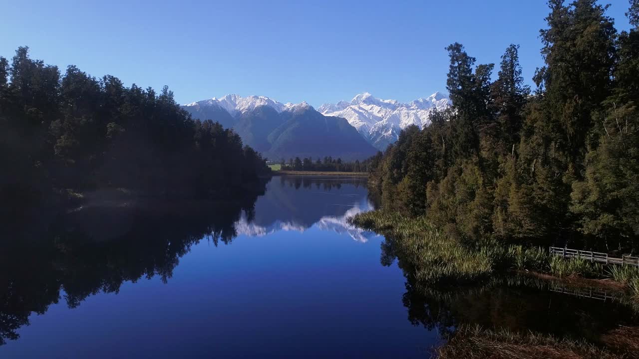 飞行在静止的冰川湖上，完美地反映出壮丽的自然景色，金色的晨光覆盖着雪山视频素材