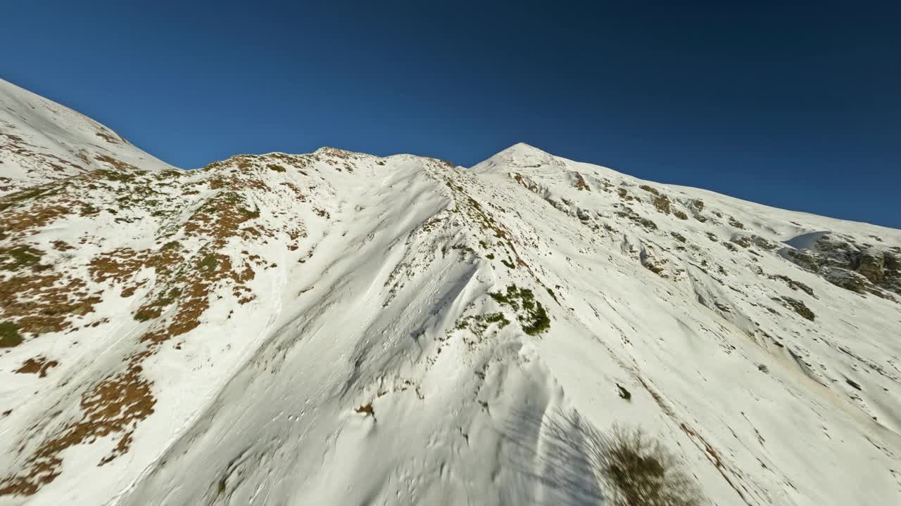 飞越山脊山顶雪景如画的小山海拔野生阳光环境鸟瞰图视频素材