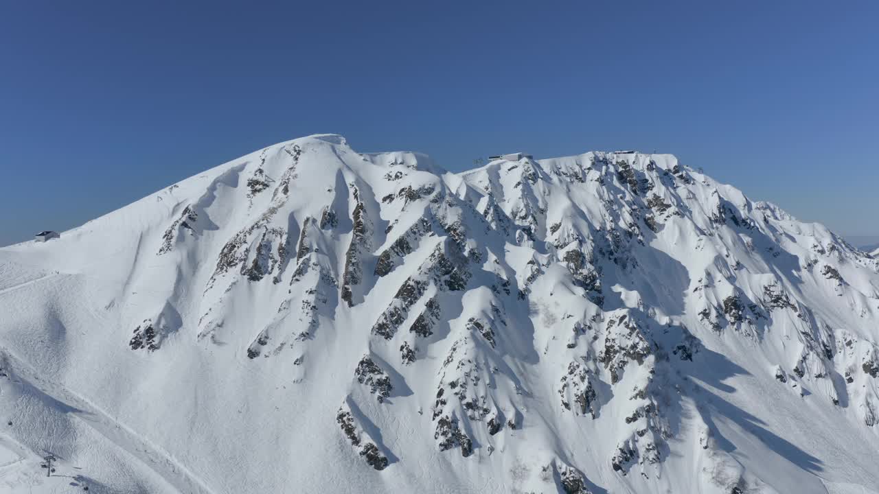 阳光明媚的滑雪场景观雪山活跃的极限运动骑手滑雪单板滑雪鸟瞰视频素材