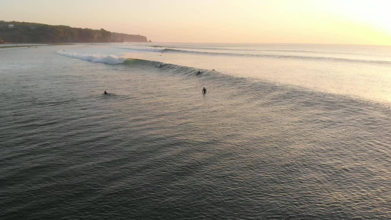 海洋的鸟瞰图与理想的海浪和冲浪者乘坐在温暖的日落波浪。视频素材