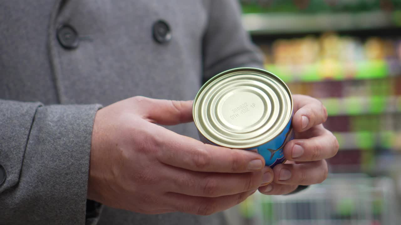 手握罐头食品的成分读保质期。视频素材